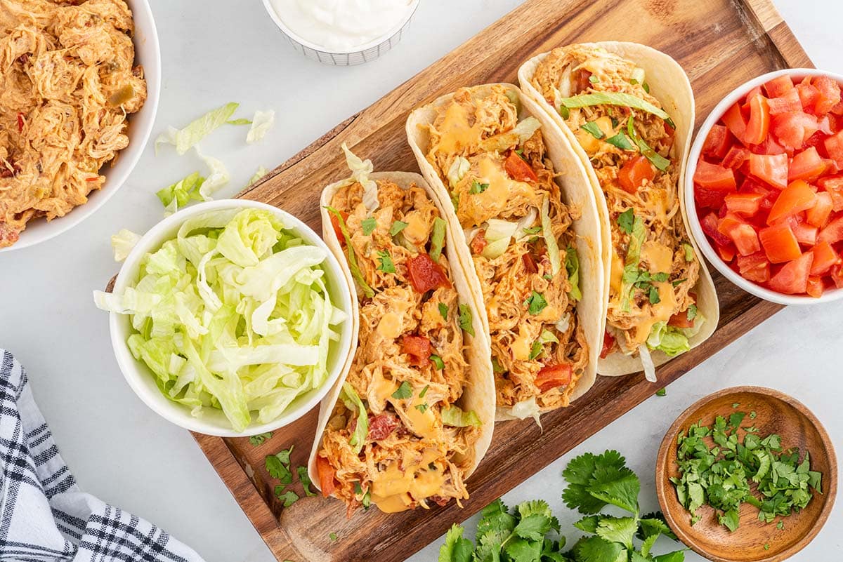slow cooker queso chicken tacos on wooden board