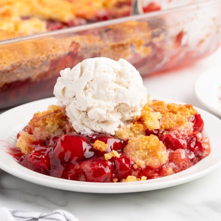 cherry dump cake served on a plate with a scoop of ice cream.