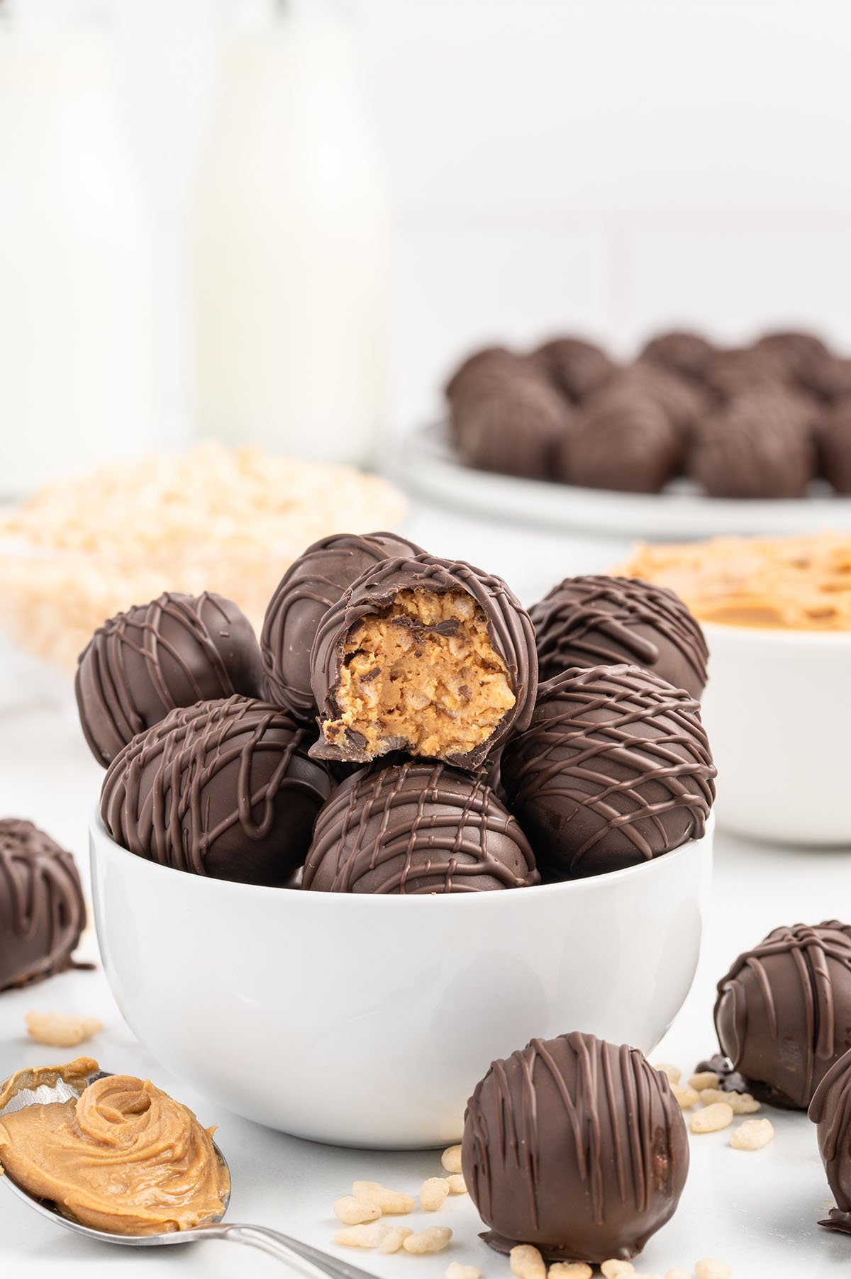 peanut butter balls with rice krispie stacked inside a white bowl.