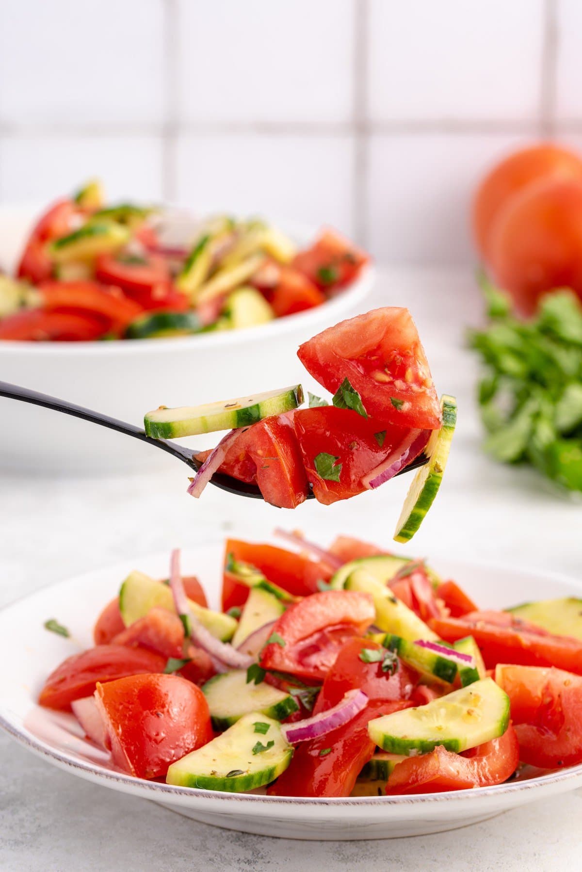 eating tomato cucumber salad with a fork