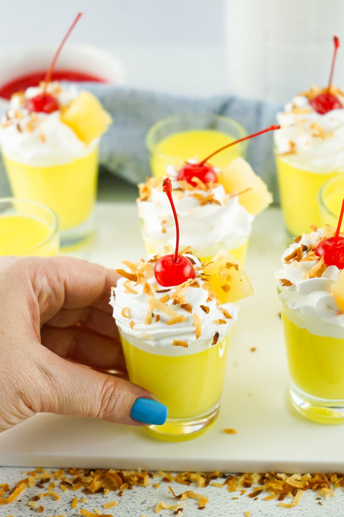 hand holding pina colada pudding shot with topping