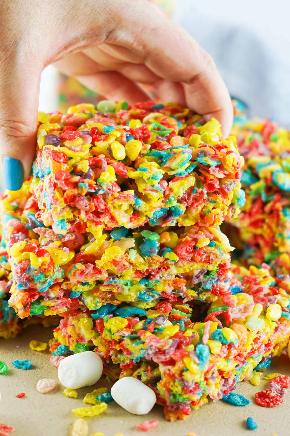 hand picking up How to Make Fruity Pebbles Rice Krispie Treats