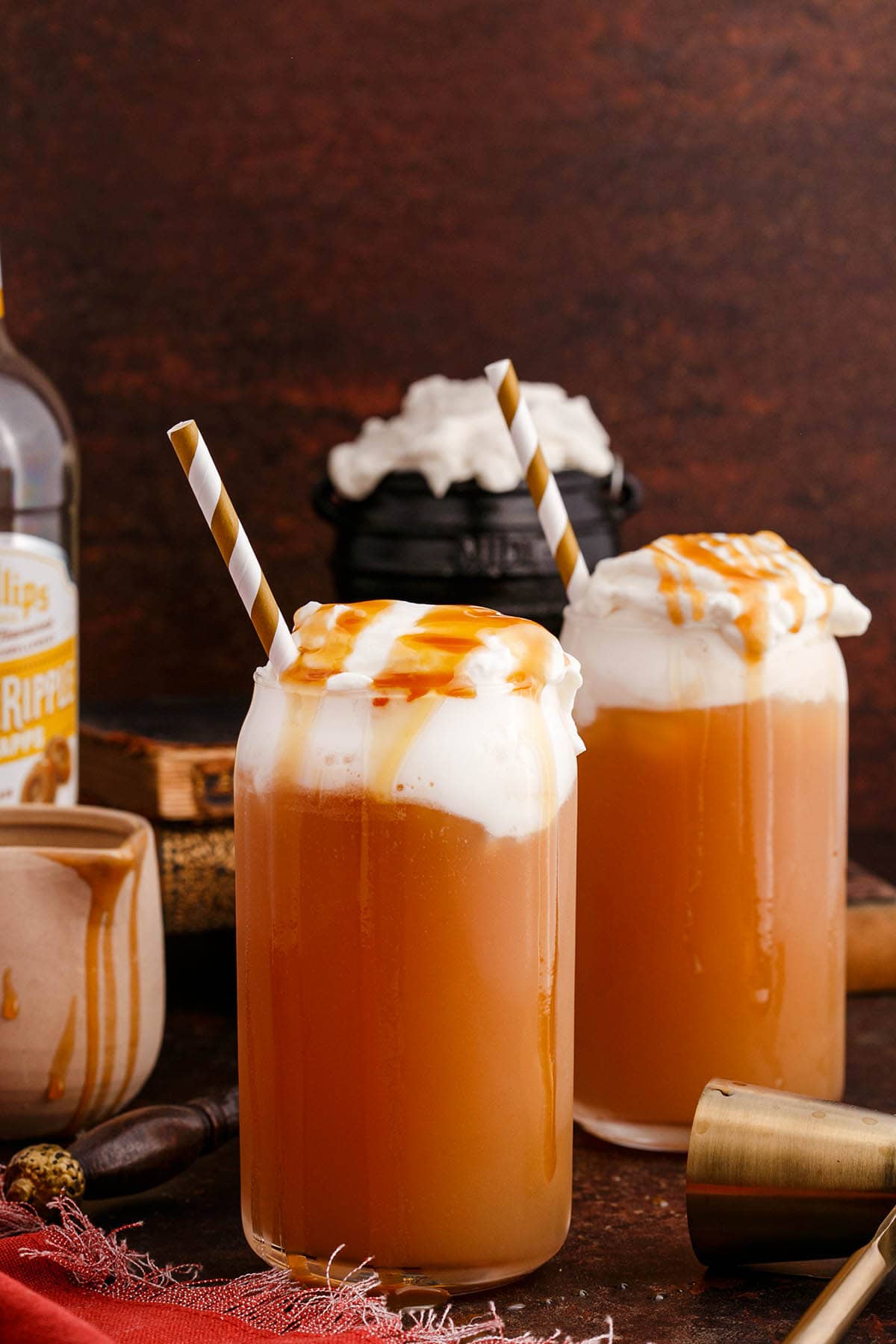 two glasses of Alcoholic Butterbeer with whipped cream on top and a drizzle of salted caramel.