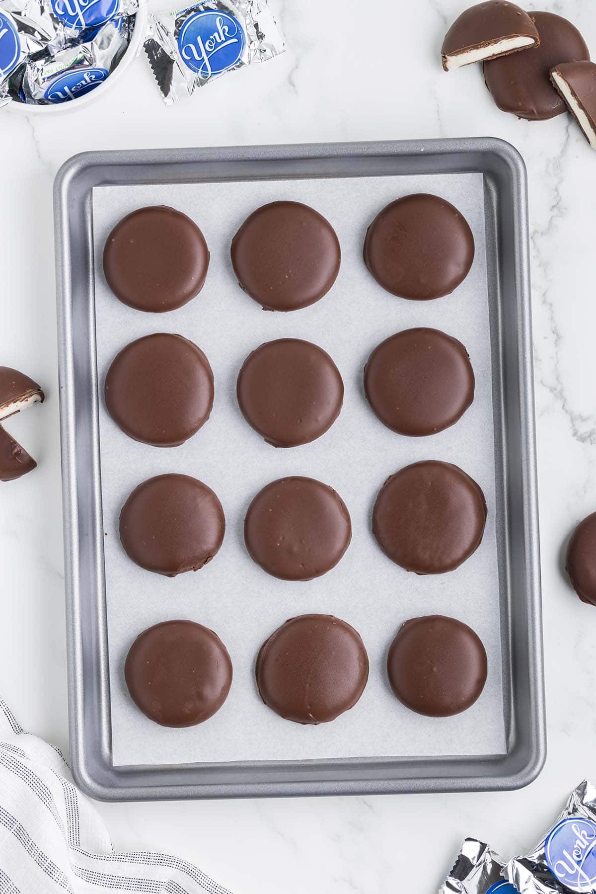 peppermint patties coated with melted chocolate on baking sheet.