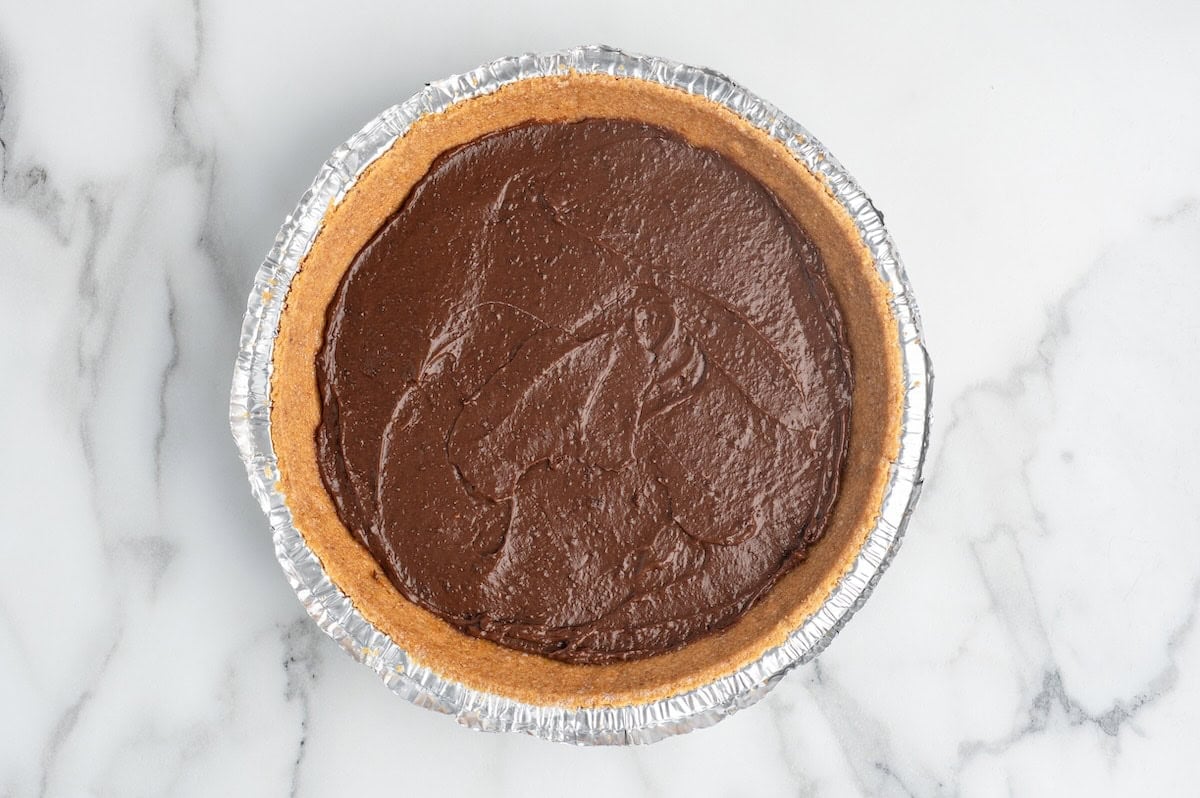 pouring chocolate pudding into the graham cracker pie.