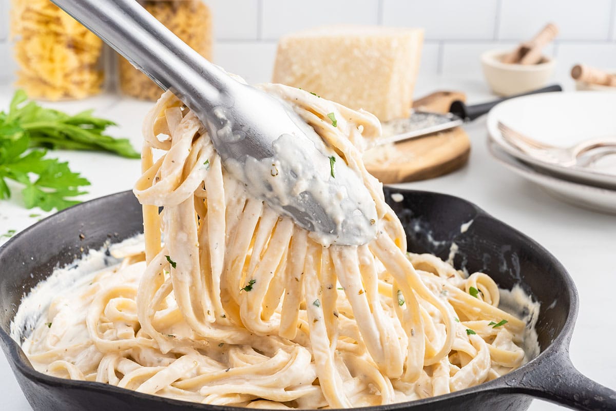 mixing cream cheese sauce with pasta
