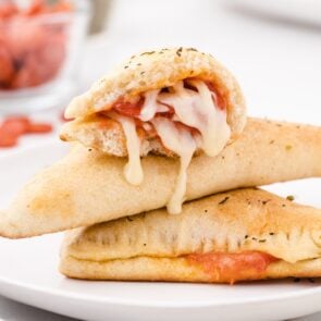 pizza pockets stacked on top of white plate.