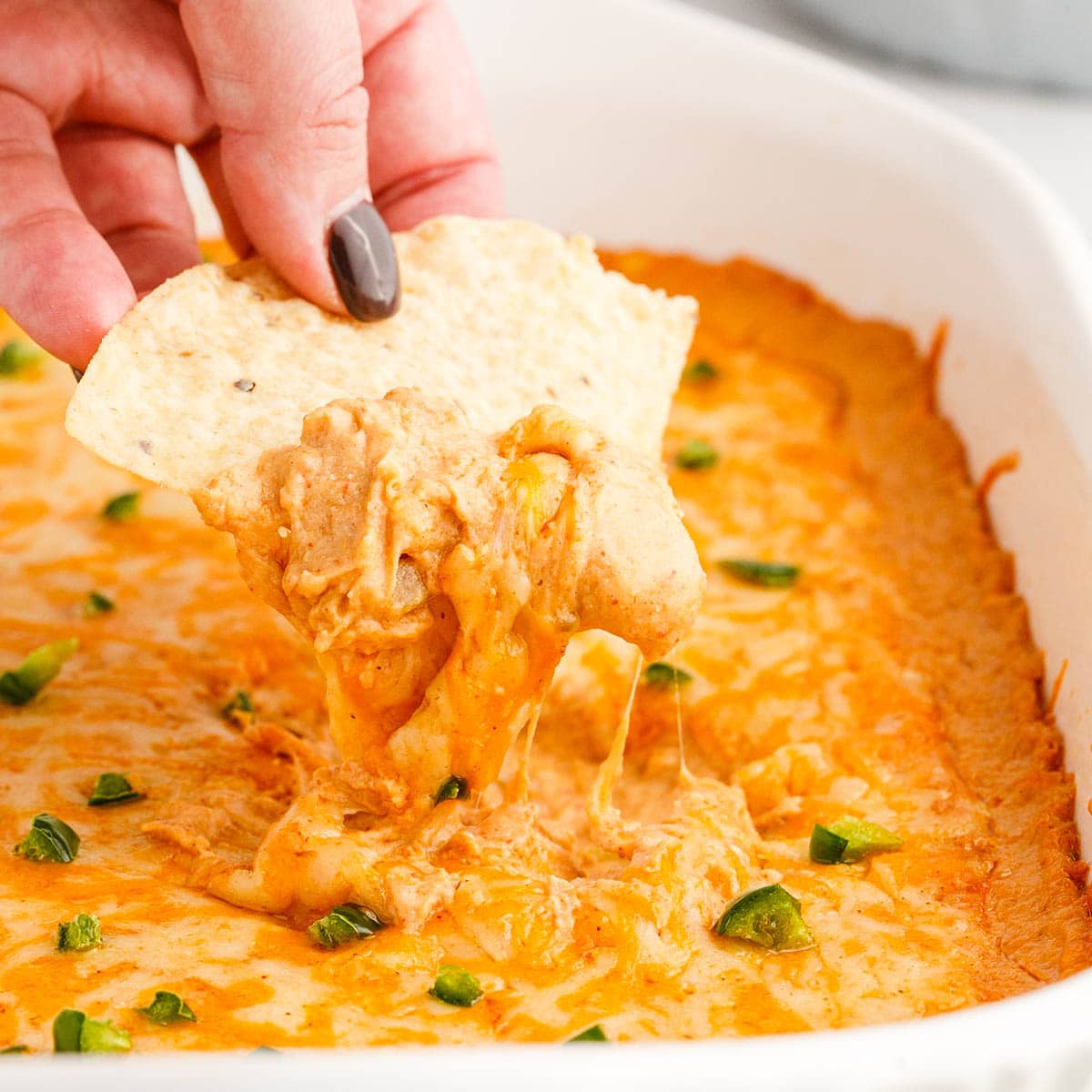 Texas Trash Dip, hand holding a chip digging into the the dip.