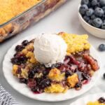 blueberry dump cake on a plate with a scoop of ice cream.
