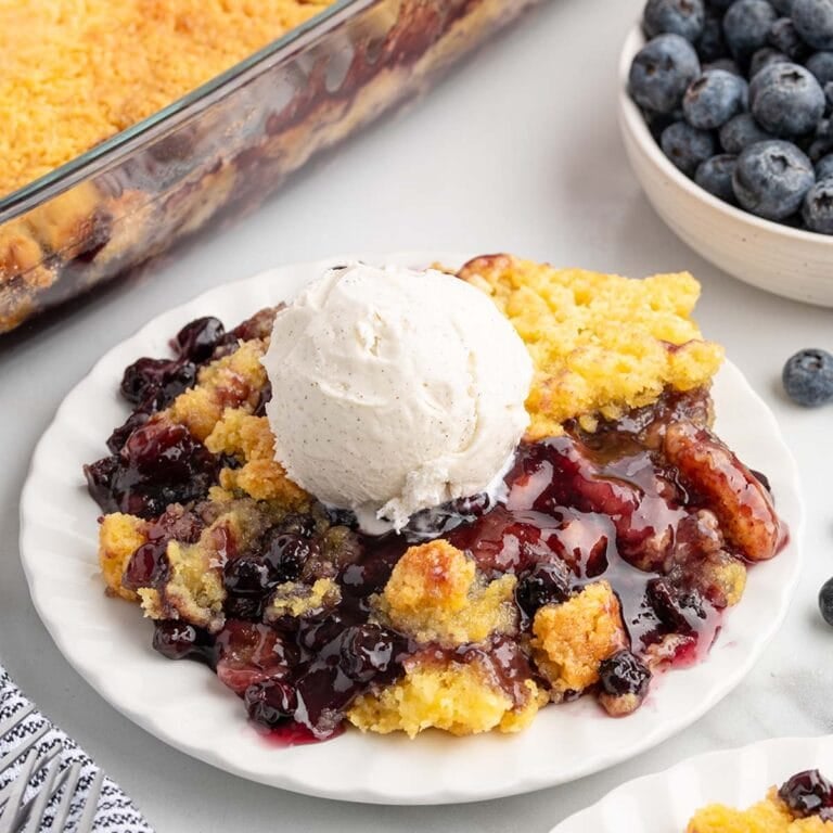 blueberry dump cake on a plate with a scoop of ice cream.