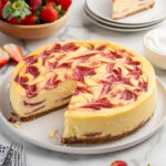 strawberry swirl cheesecake with a triangle piece missing.