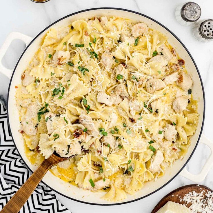 Creamy Bowtie Pasta with chicken and parmesan in a skillet.