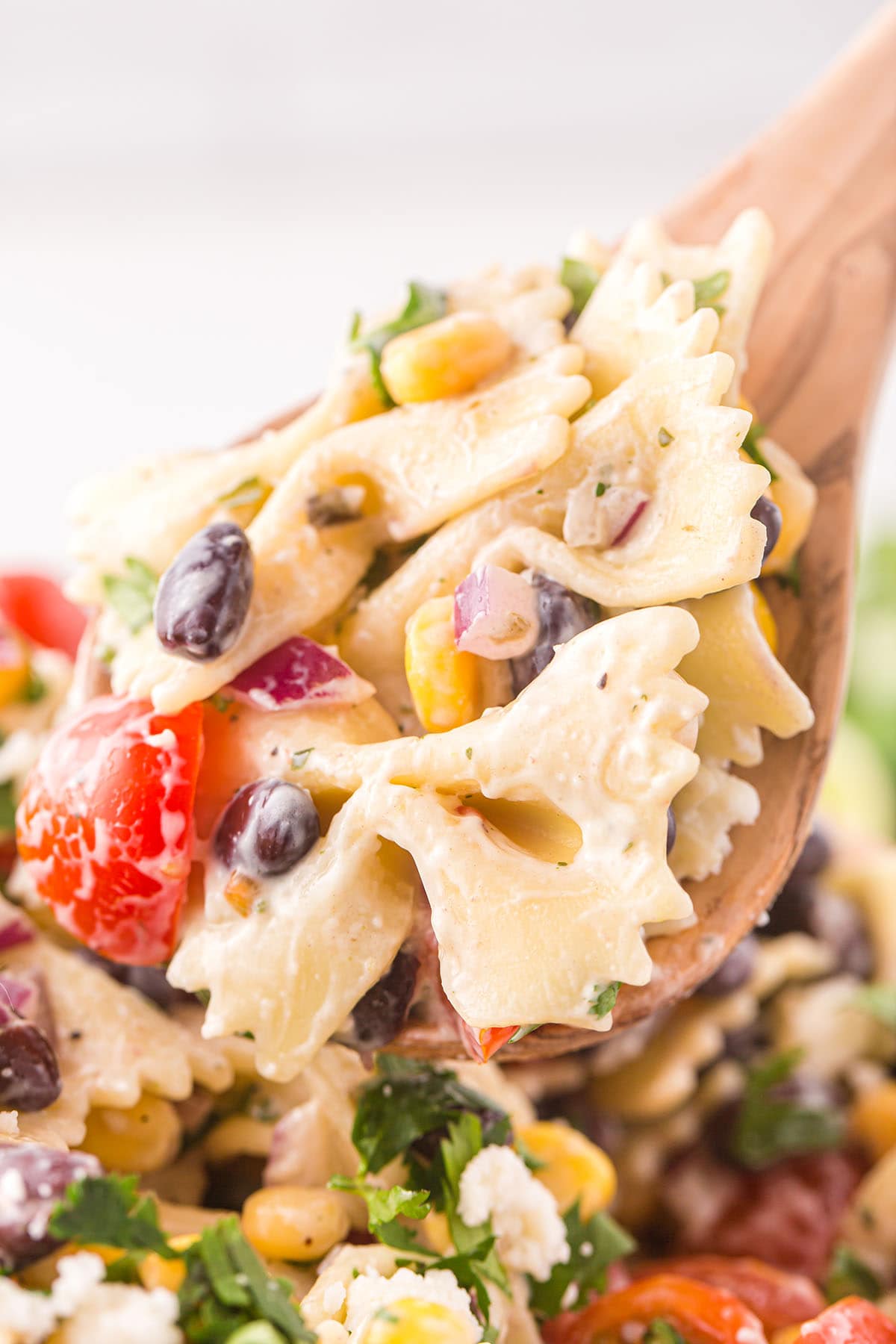 scooping Mexican Pasta Salad with wooded spoon