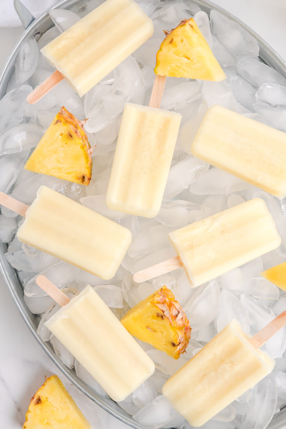 a couple of Boozy Dole Whip Popsicles on top of bucket of ice