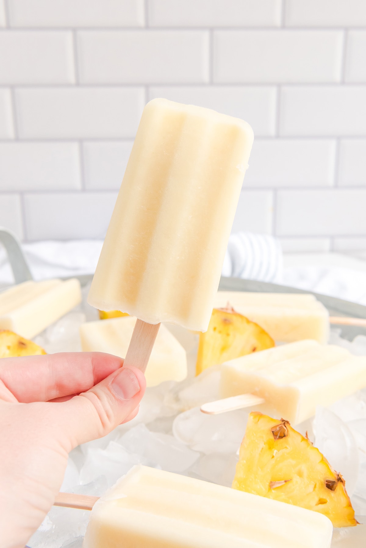 hand holding Boozy Dole Whip Popsicles