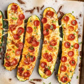 pizza zucchini boats on top of parchment paper