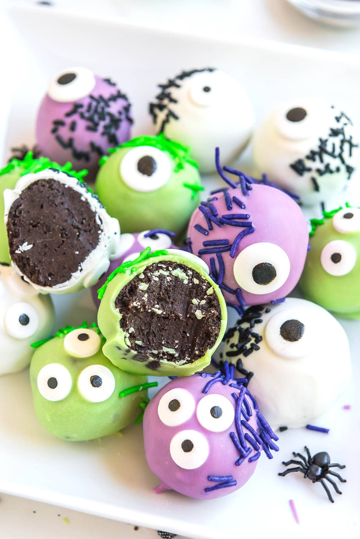 green and purple Monster Oreo Balls on a white table.