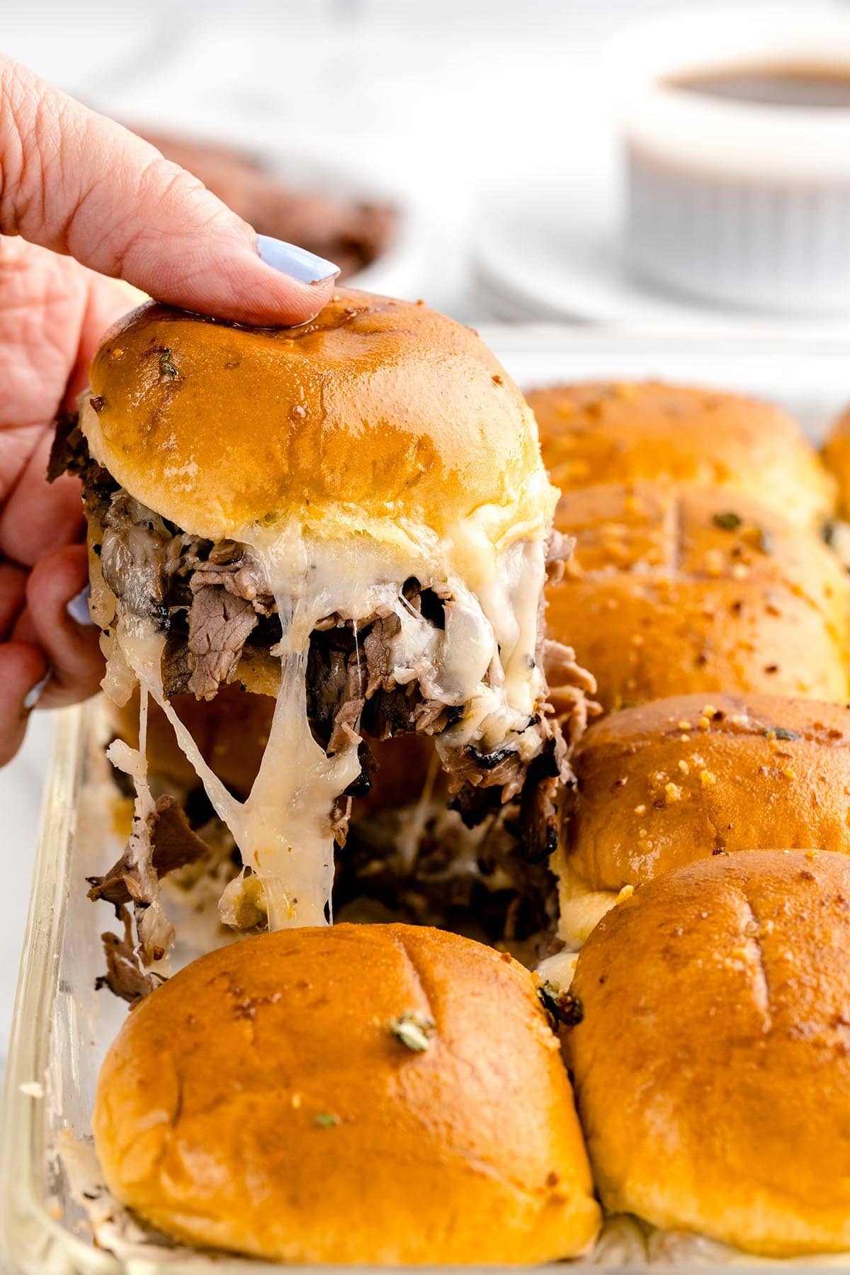taking 1 french dip slider from the casserole dish