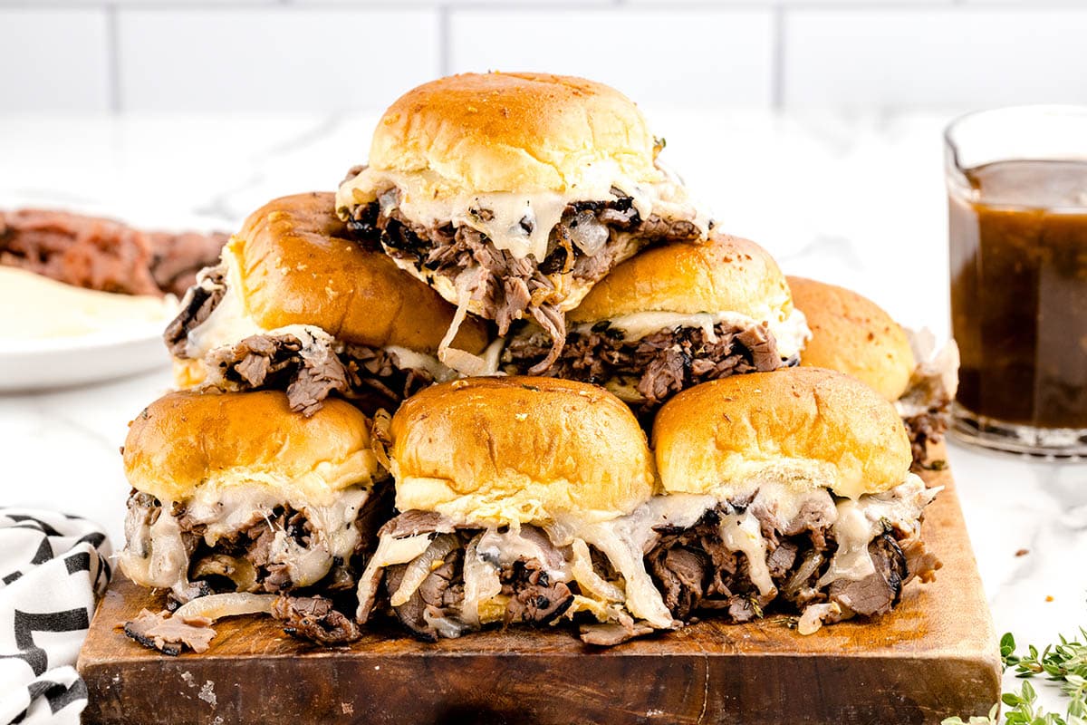 a couple of French Dip Sliders stacked on top of wooden board