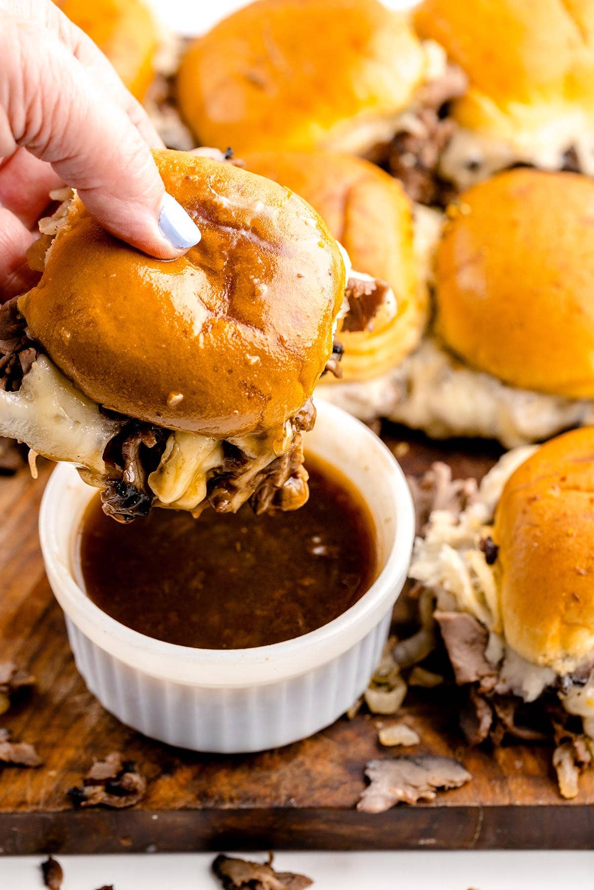 dipping the sliders into a bowl of sauce