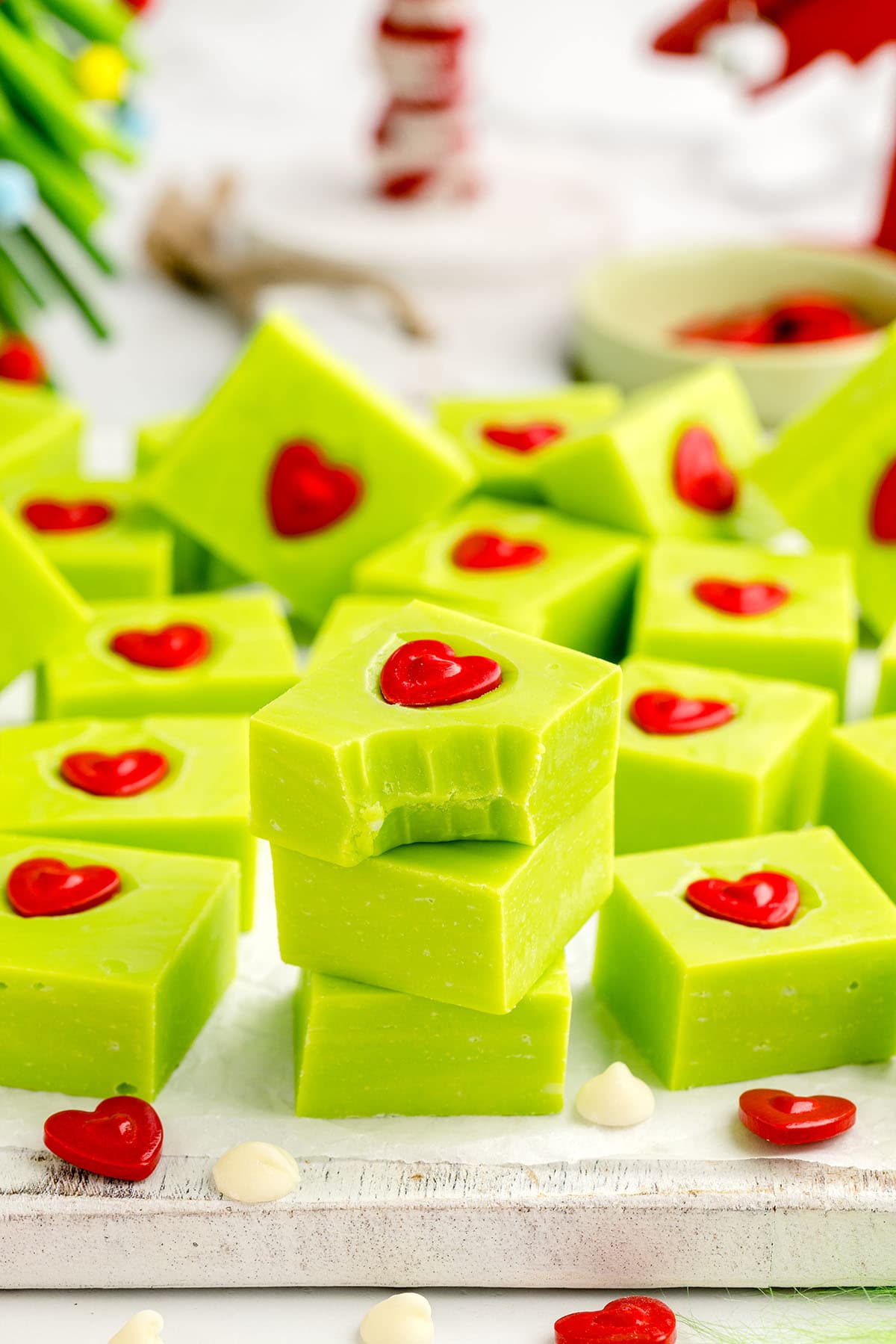 Grinch Fudge with a red heart candy stacked with a bite out of the top piece.