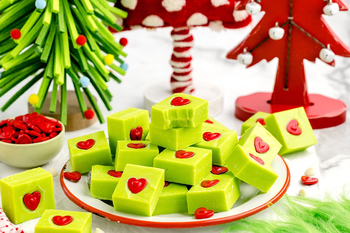 a pile of Grinch Fudge on a white plate and Christmas tree on the background.