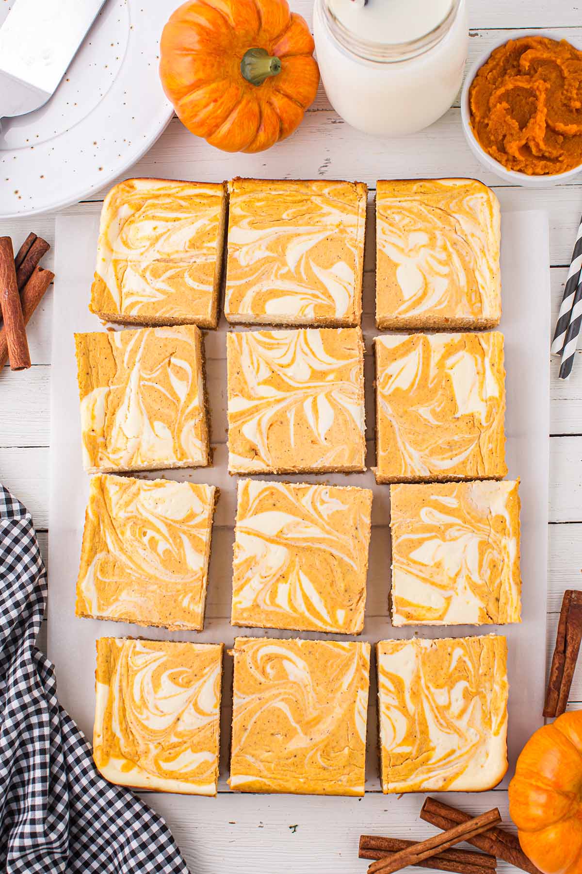 Pumpkin Cheesecake Bars cut into squares with a glass of milk on the background.
