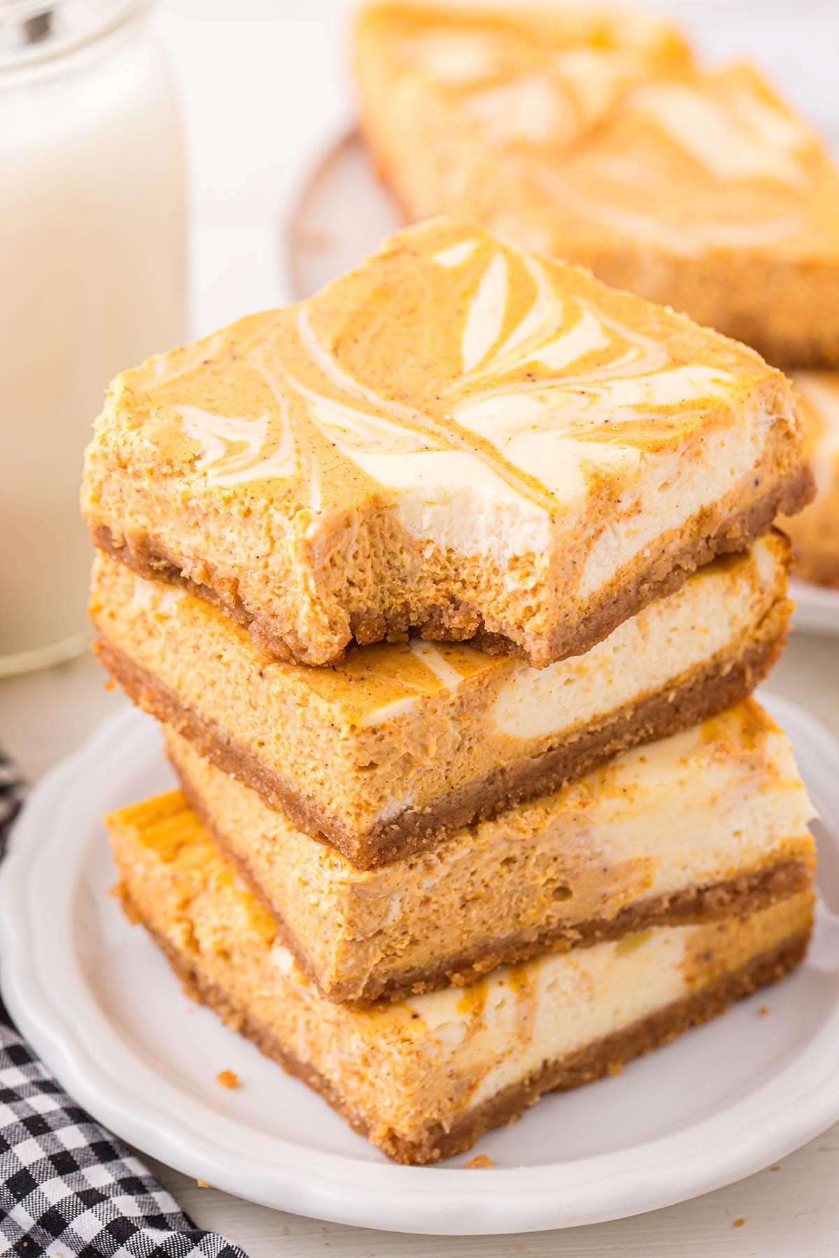 a couple of Pumpkin Cheesecake Bars stacked on a white plate.
