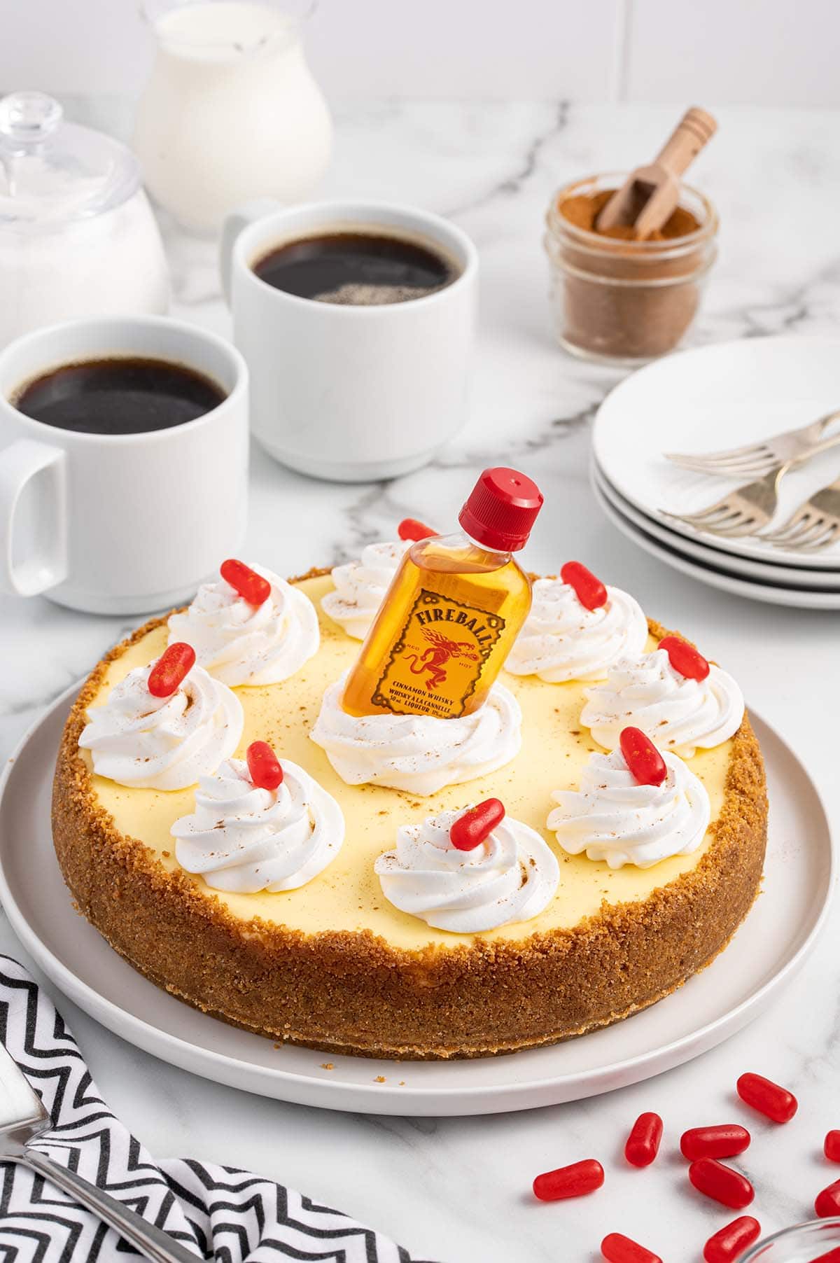 Fireball Cheesecake on a white table with small fireball whiskey bottle on top of the cheesecake.
