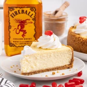 Fireball Cheesecake on a plate with fireball bottle on the background.
