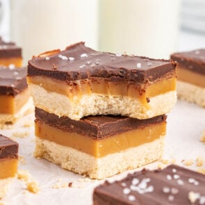 bitten Millionaire Shortbread stacked on top of white table.