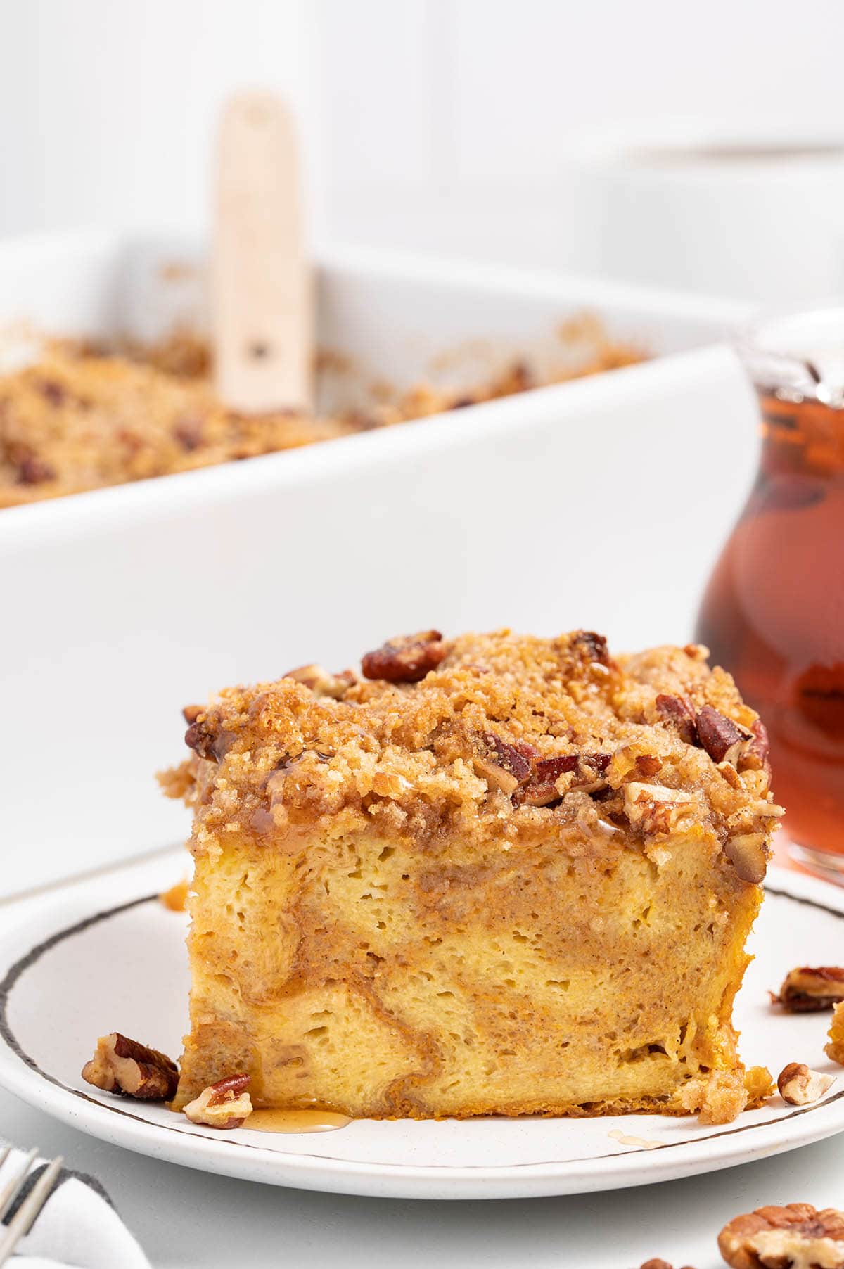 a slice of Pumpkin French Toast Casserole on a plate with casserole dish on the background.