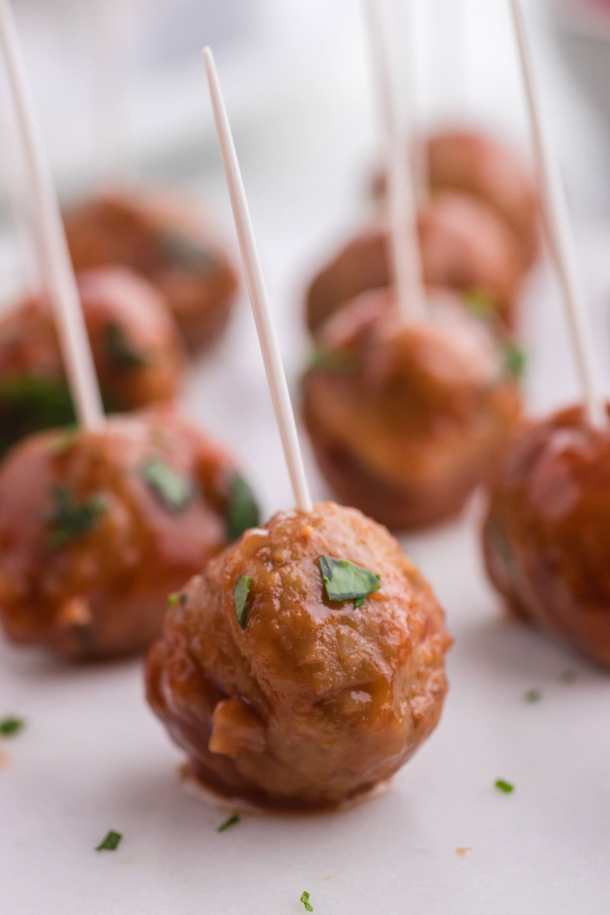 sticking toothpick into cranberry meatballs to serve as snack.