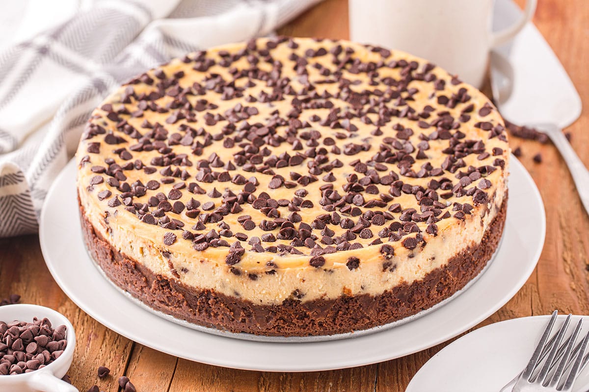Chocolate Chip Cheesecake on a white plate with a glass of milk on the background.