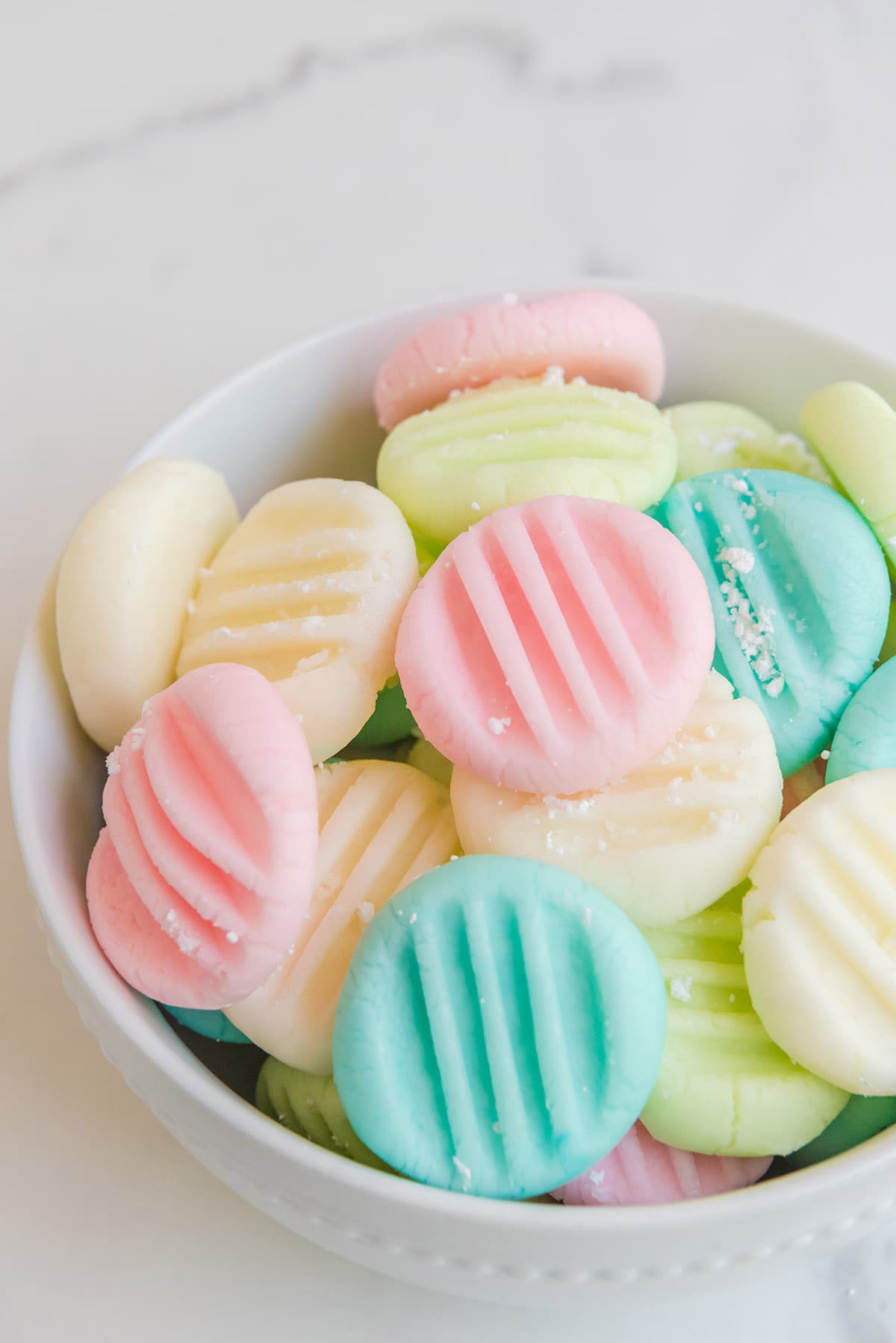multi colored cream cheese mints in a bowl.