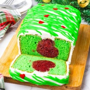 Grinch Cake on a large wooden board with heart sprinkles.
