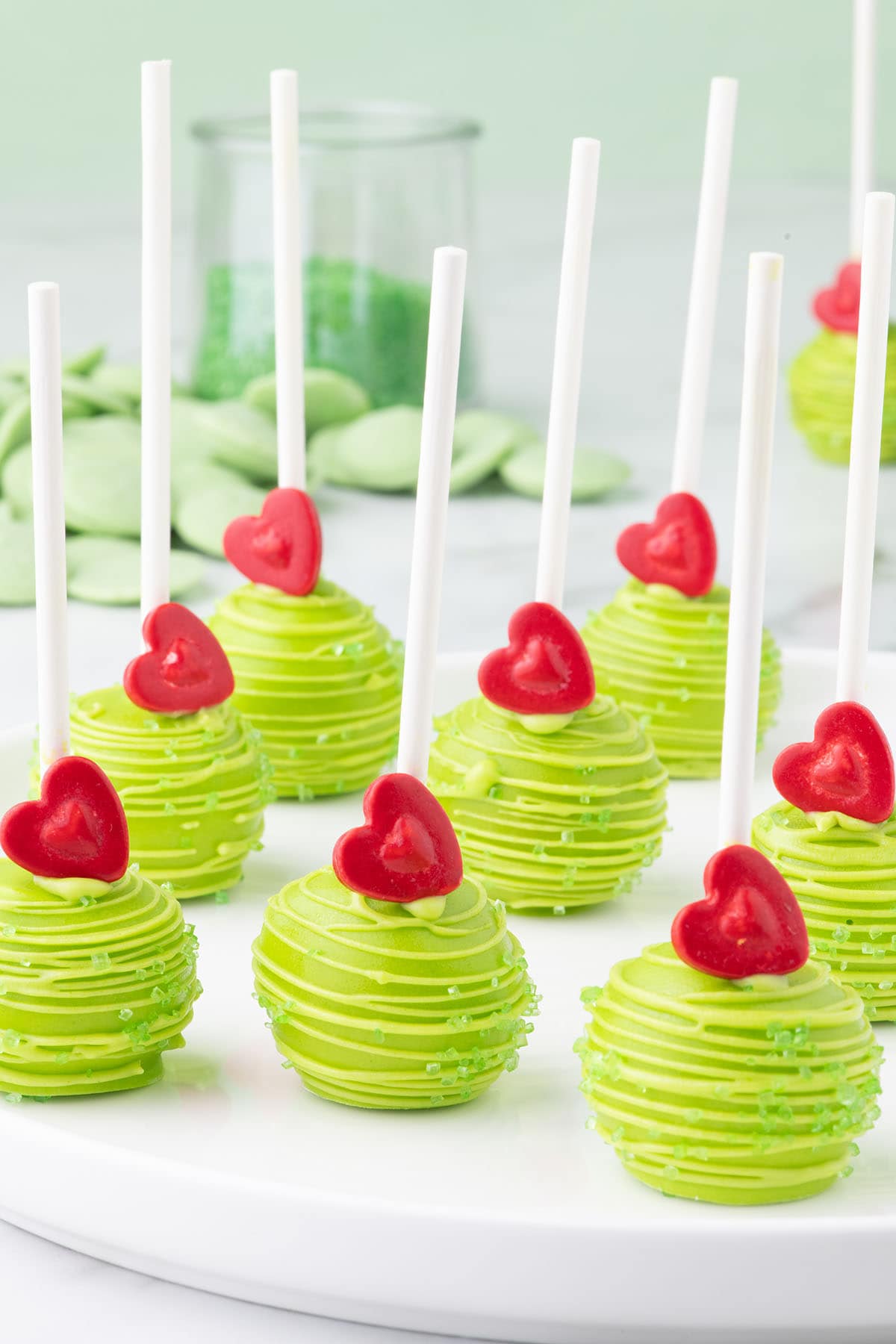 Grinch Cake Pops with a candy heart on top in a plate. 