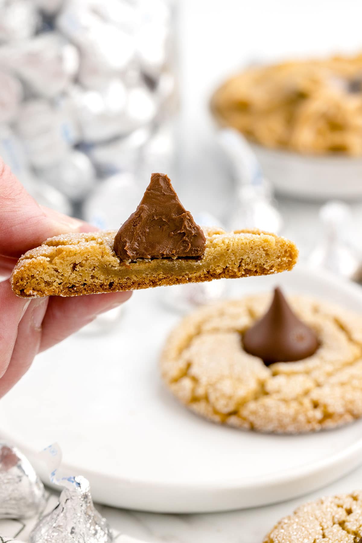 hand holding half of Peanut Butter Blossoms with hershey's kiss in the center.