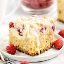 Raspberry Coffee Cake on a white plate with white chocolate drizzle.