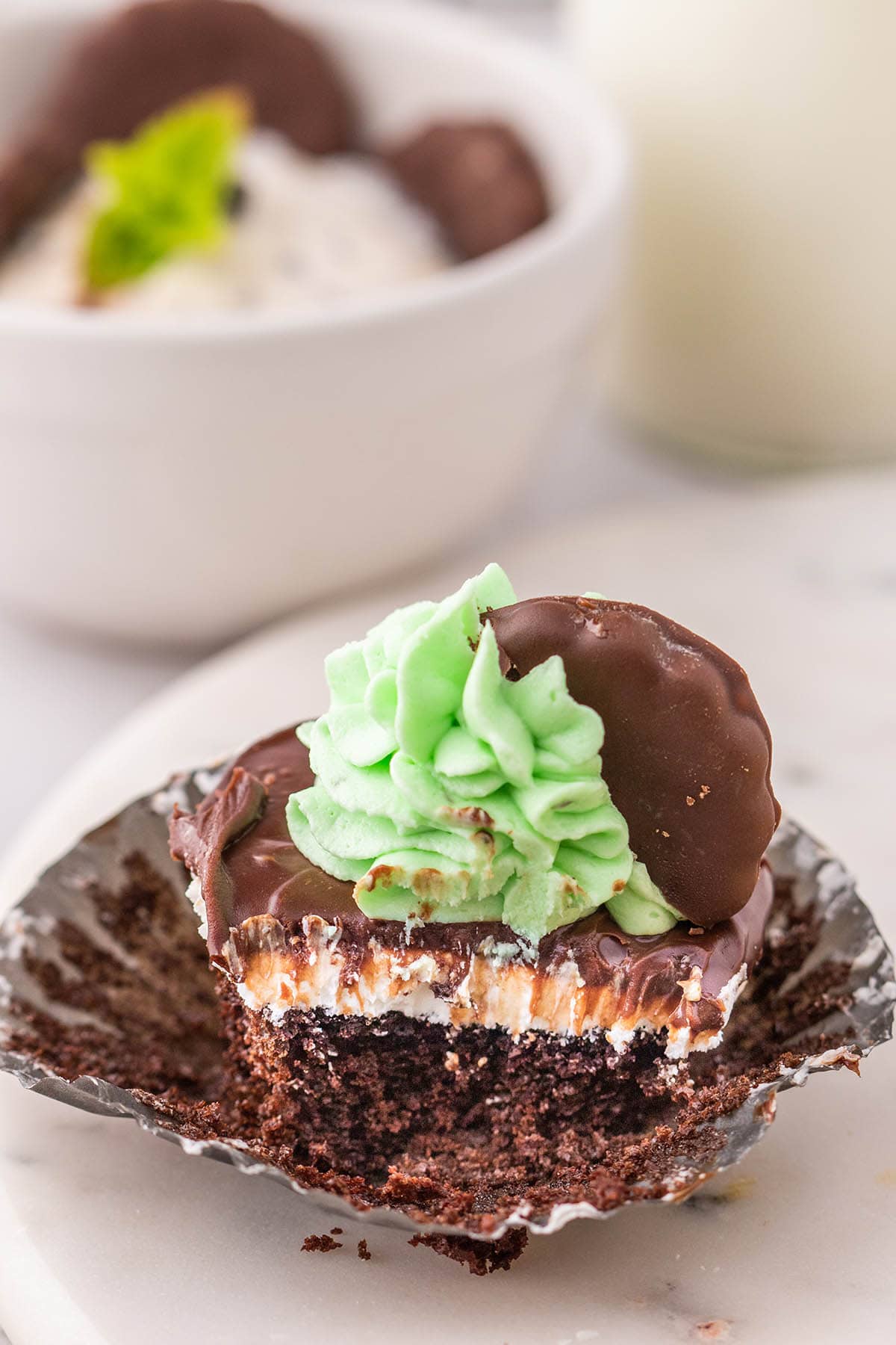bitten Thin Mint Cupcakes and a white bowl on the background.