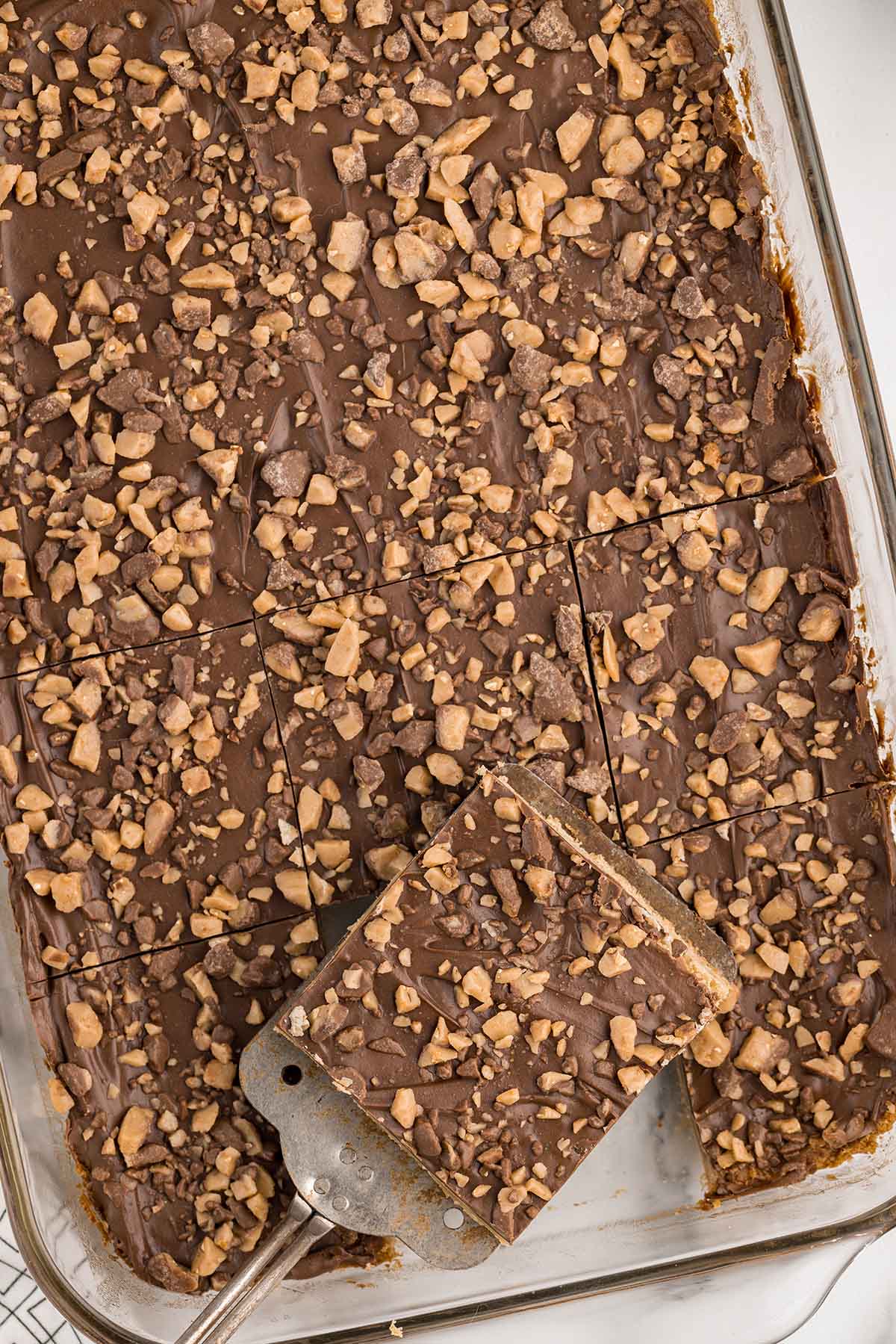 Toffee Bars in a baking dish with one slice on a spatula.