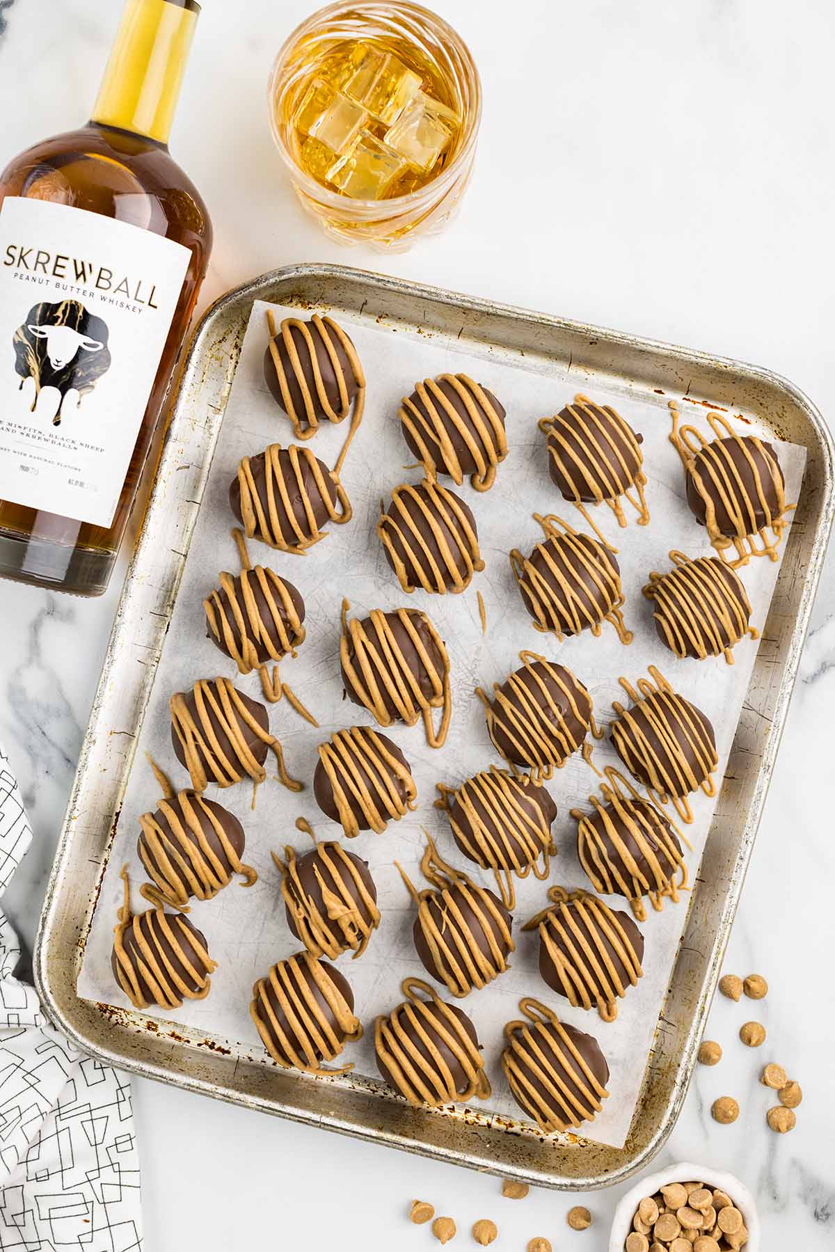 Whiskey Balls on a baking sheet with a bottle of Screwball whiskey beside it.