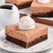 French Silk Brownies with a dollop of whipped cream and chocolate shavings on top.