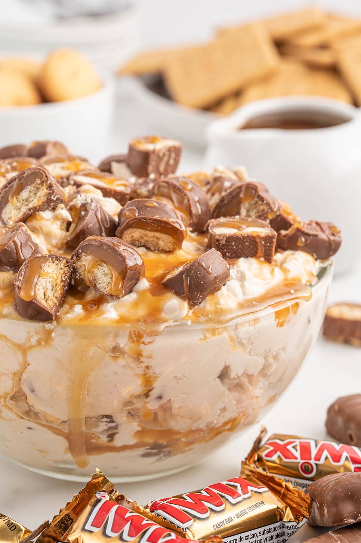 a bowl of Twix Dip with small candy bars on top.