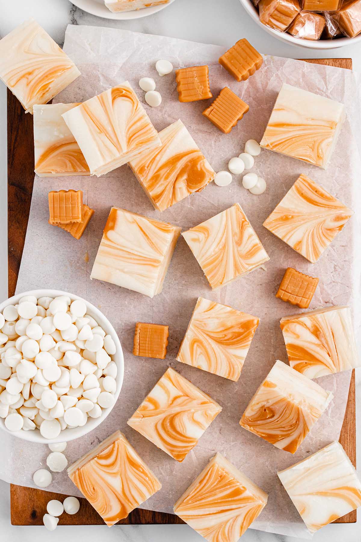 White Chocolate Caramel Fudge on top of wooden board with white chips in a bowl.