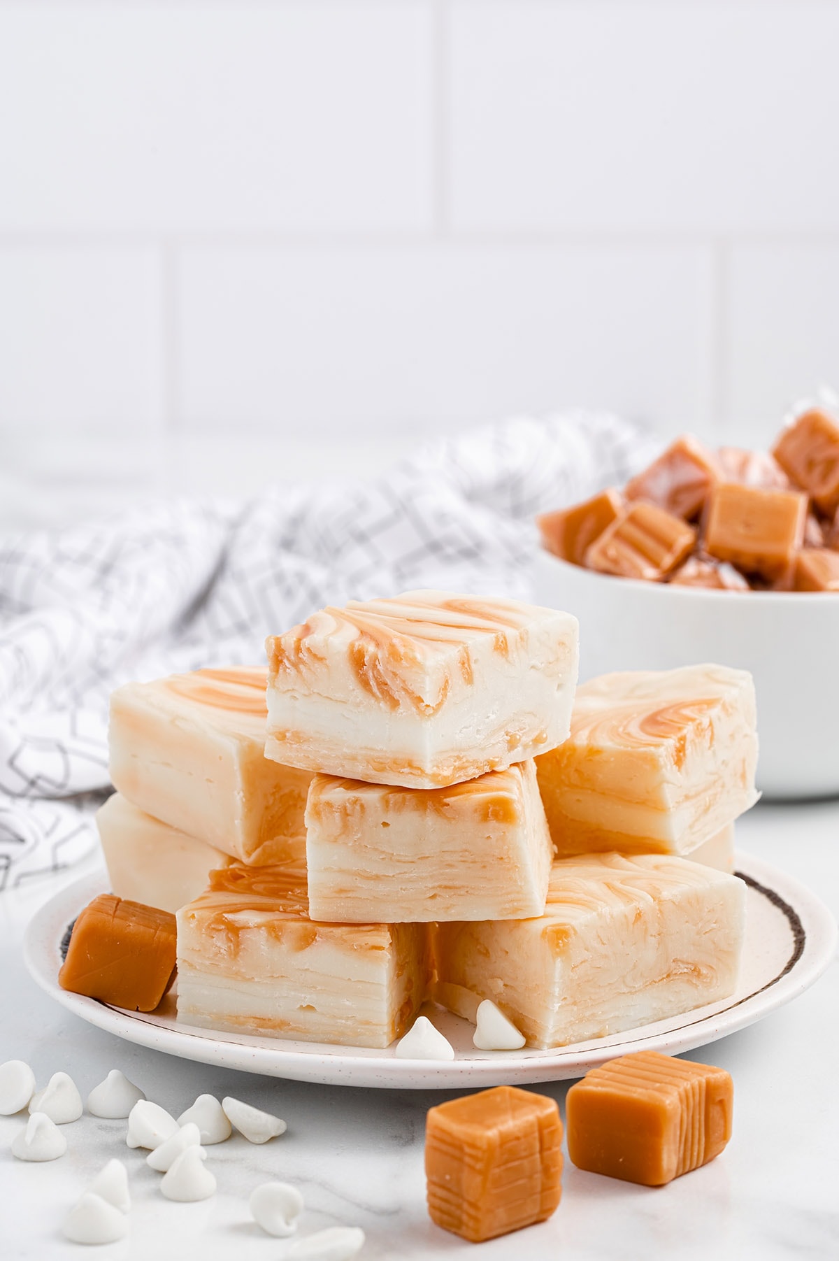 a couple of White Chocolate Caramel Fudge stacked on a white plate.