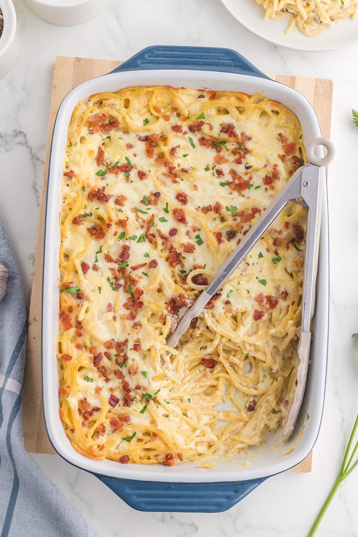 Creamy Bacon Spaghetti in a baking dish with bacon and cheese on top.