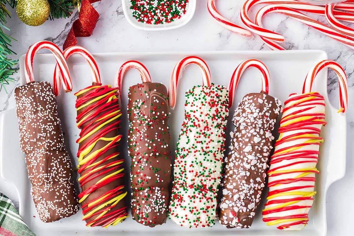 6 pieces of Christmas Marshmallow Pops with candy cane and toppings in a white plate.