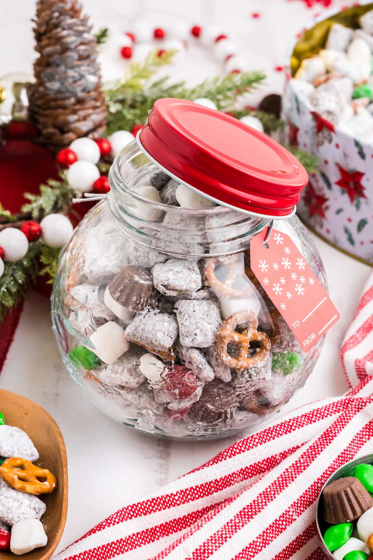 Christmas Puppy Chow in a glass jar with a red lid