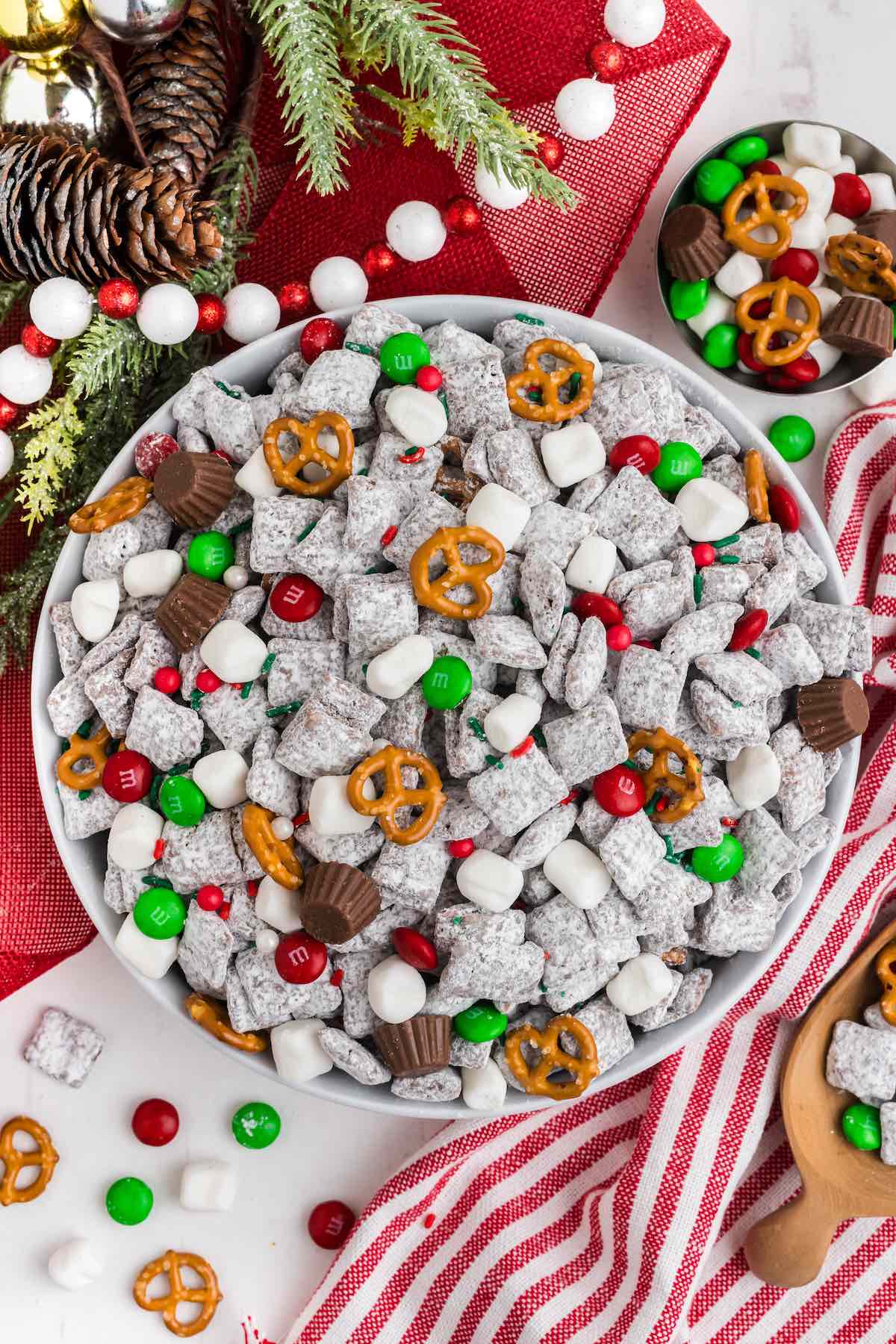 Christmas Puppy Chow in a bowl with christmas decoration at the back.